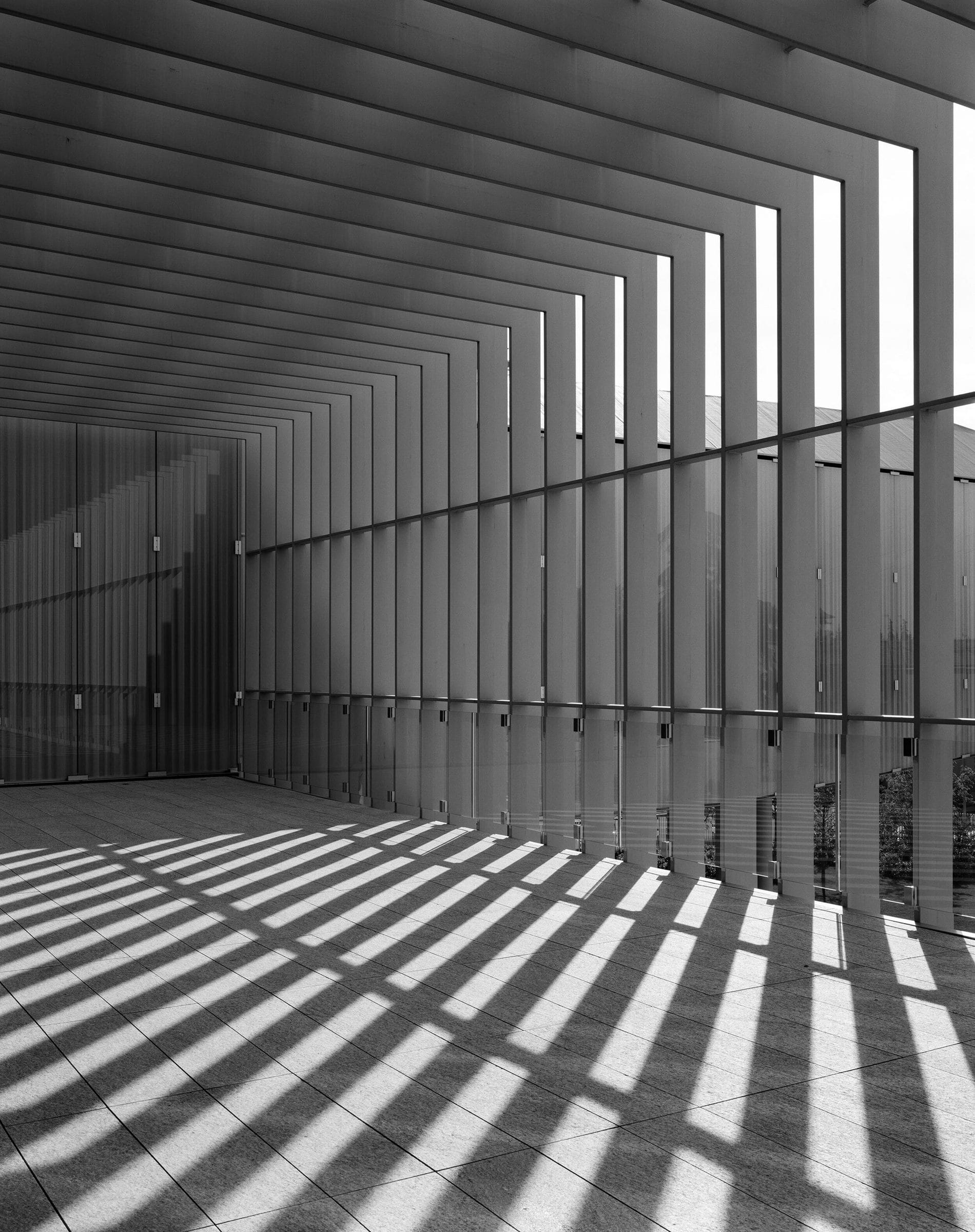 Le lamelle della facciata proiettano ombre sul pavimento della terrazza