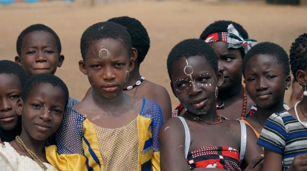 Un gruppo di bambine e bambini con il viso dipinto guarda verso la camera, in una scena del film