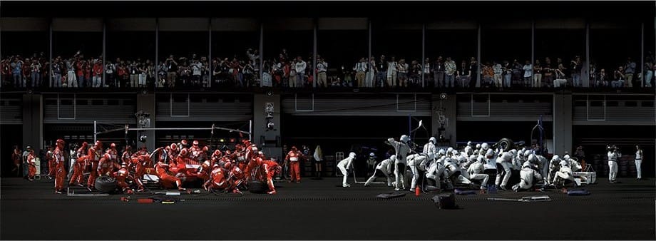 Il pit stop di due monoposto di Formula 1, con le squadre ai box e il pubblico sopra