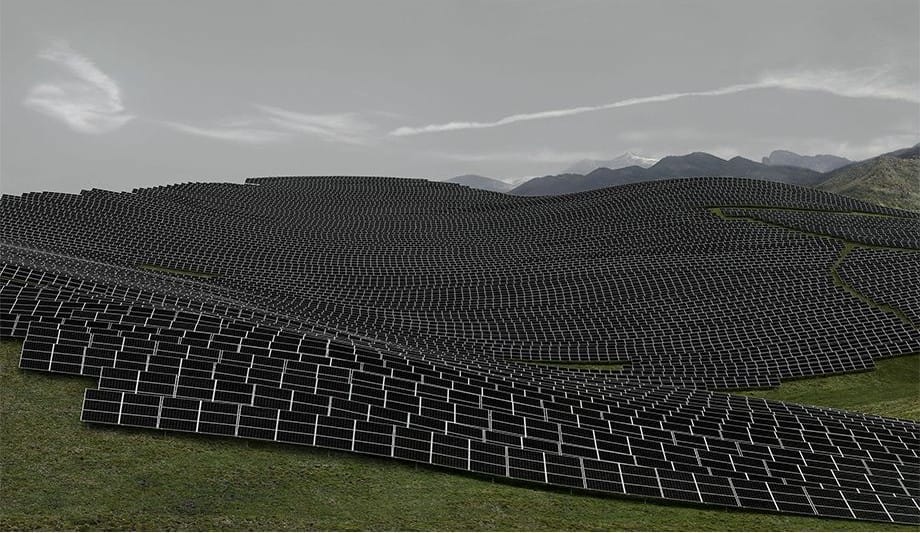 Distese di pannelli solari su colline, sotto un cielo grigio