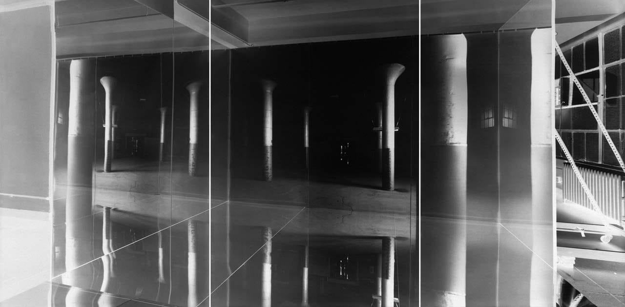 Fotografia in negativo: un ambiente con colonne e grandi vetrate riflesso sull’acqua