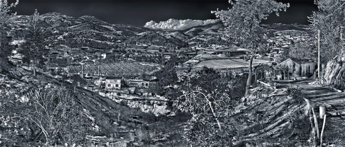 Un campo profughi con tende tra colline e mare, in un’immagine termica in bianco e nero