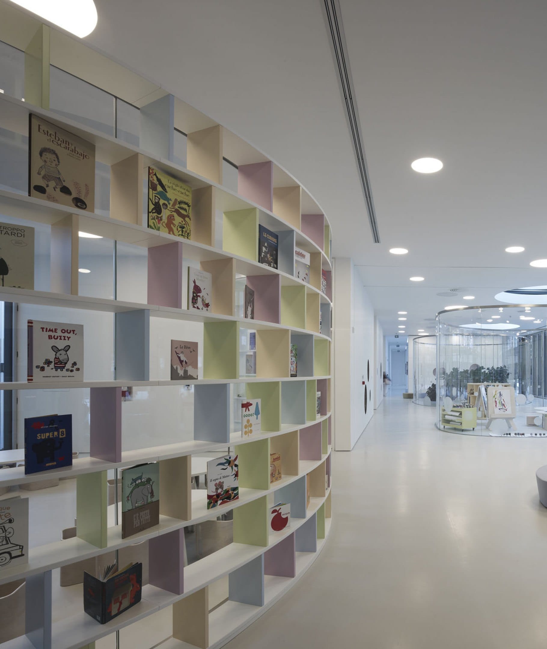La libreria curva di libri illustrati e il corridoio verso l’atelier