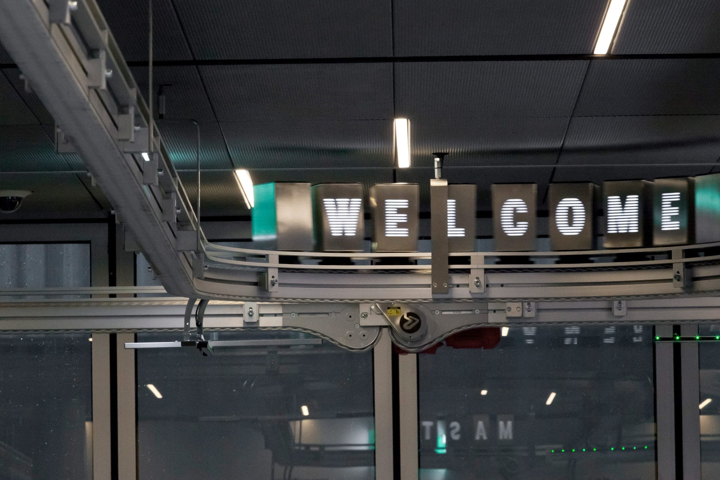 La scritta WELCOME in lettere metalliche sospese sopra l’ingresso vetrato del MAST