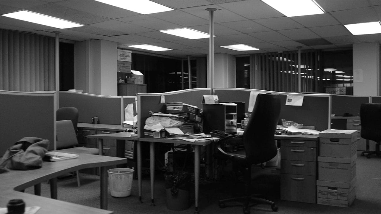 Un ufficio vuoto con scrivanie e sedie, in bianco e nero